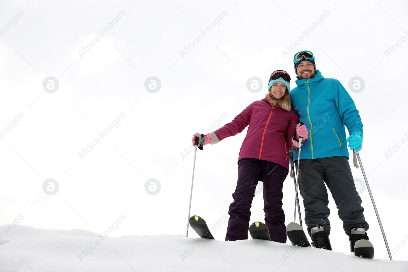 Photo of Couple of skiers on slope at resort, space for text. Winter vacation