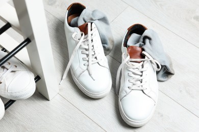 Sneakers with dirty socks on white wooden floor indoors