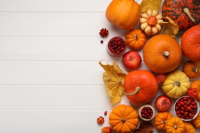 Photo of Flat lay composition with autumn leaves, berries and pumpkins on white wooden table, space for text