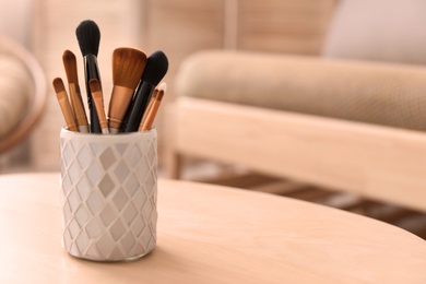 Holder with makeup brushes on table