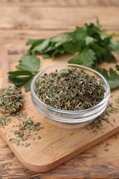 Photo of Dried parsley and fresh leaves on wooden table, closeup