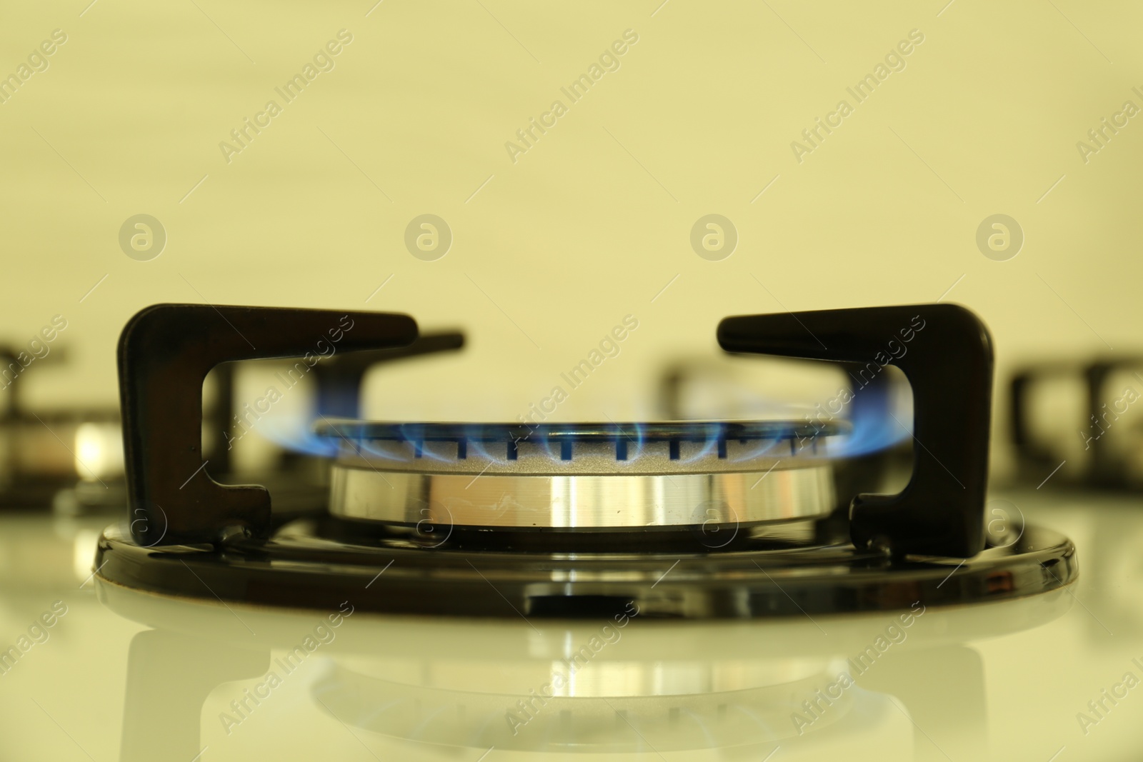 Photo of Gas burner of modern stove with burning blue flame, closeup