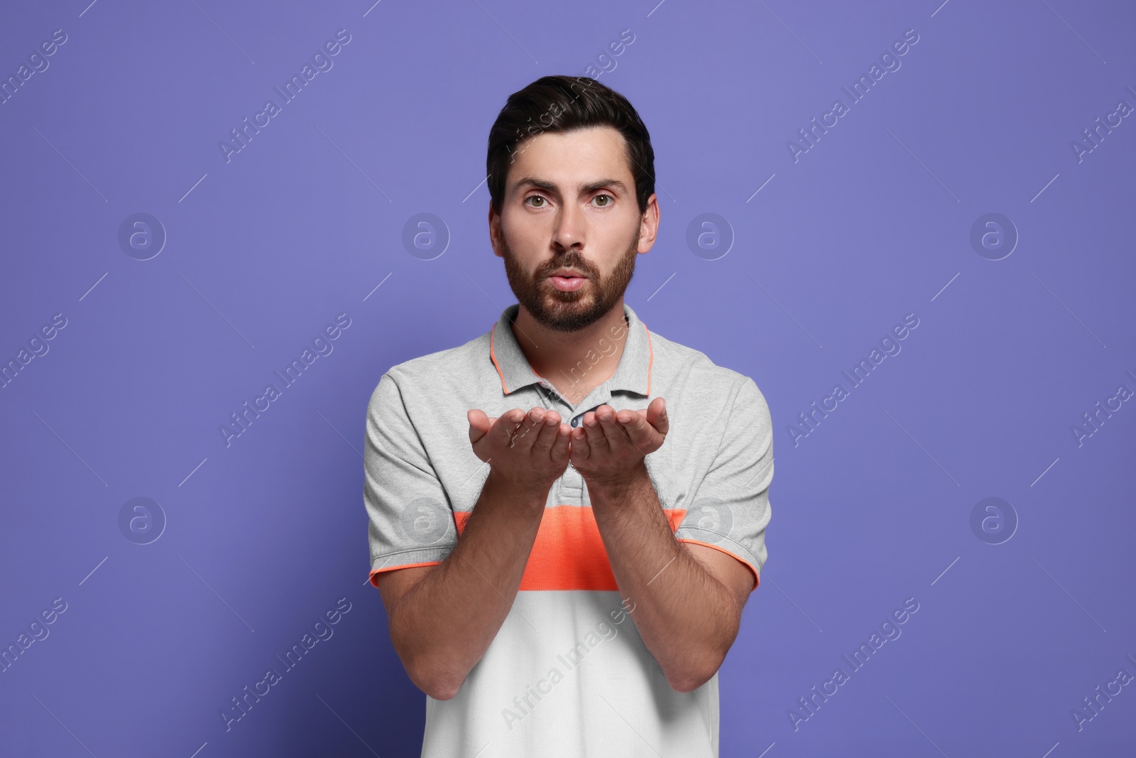 Photo of Handsome man blowing kiss on violet background