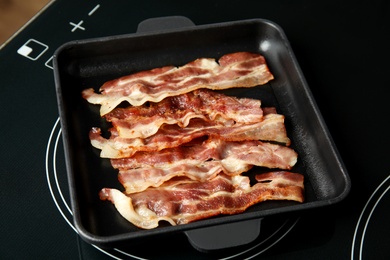 Slices of tasty fried bacon on kitchen stove