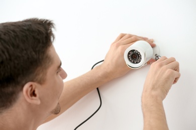 Photo of Technician installing CCTV camera on wall indoors