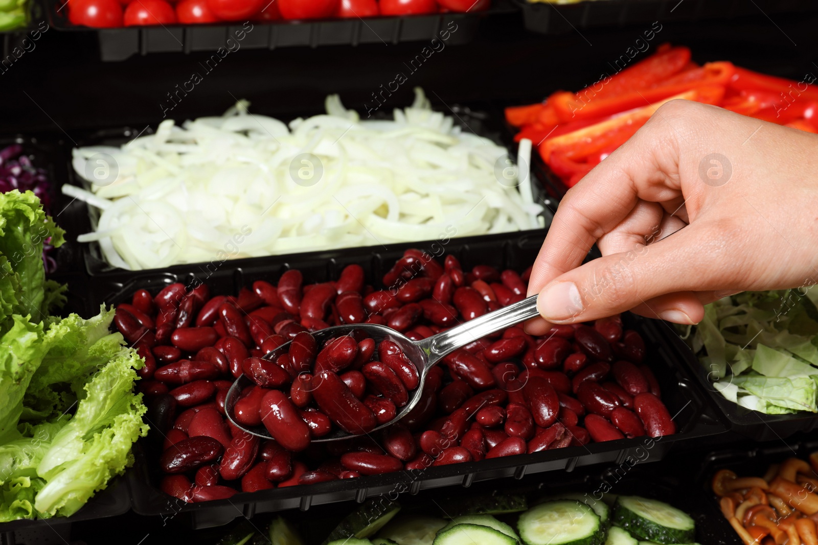 Photo of Young woman taking canned red kidney beans from salad bar, closeup