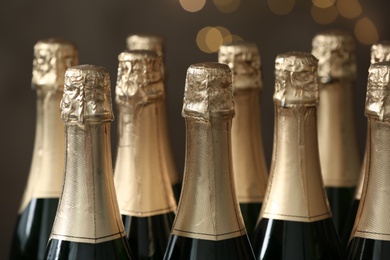 Photo of Many bottles of champagne on blurred background, closeup