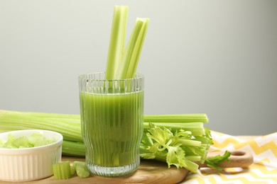 Glass of celery juice and fresh vegetables on table