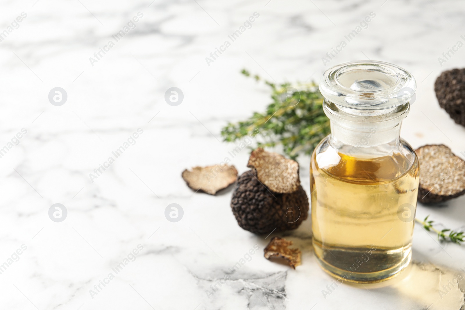 Photo of Fresh truffle and oil on white marble table, closeup. Space for text