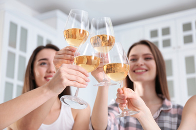Photo of Beautiful young ladies toasting at home, focus on hands with glasses. Woman's Day
