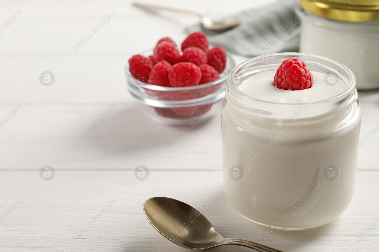Photo of Bowl with delicious yogurt and raspberry on white wooden table, closeup. Space for text