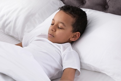 Photo of Cute little African-American boy sleeping in bed