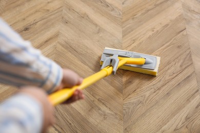 Woman cleaning parquet floor with mop, above view