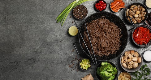 Photo of Wok with noodles, chicken and other products on grey table, flat lay. Space for text