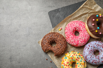Delicious glazed donuts on grey table, flat lay. Space for text