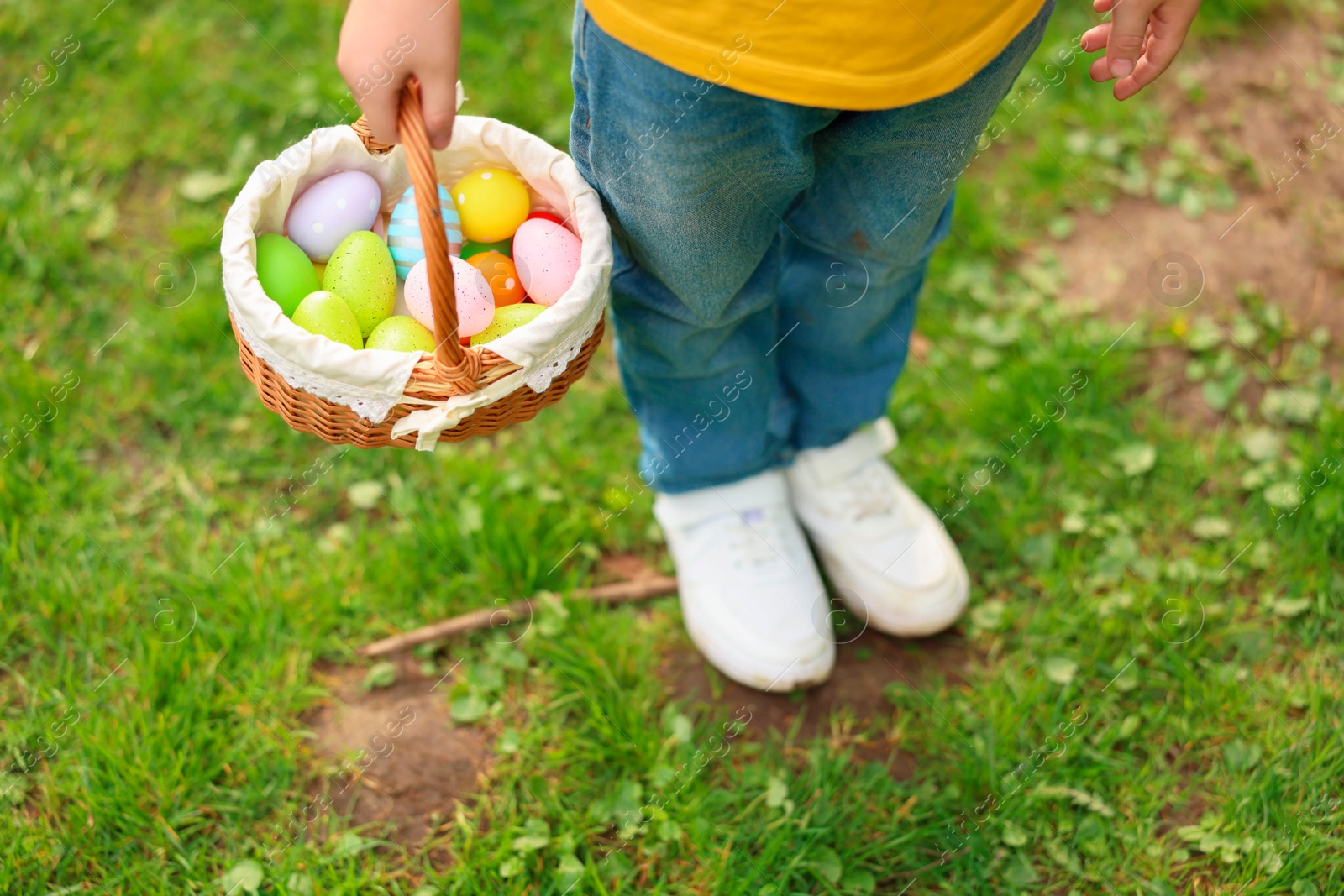 Photo of Easter celebration. Little boy holding basket with painted eggs outdoors, closeup