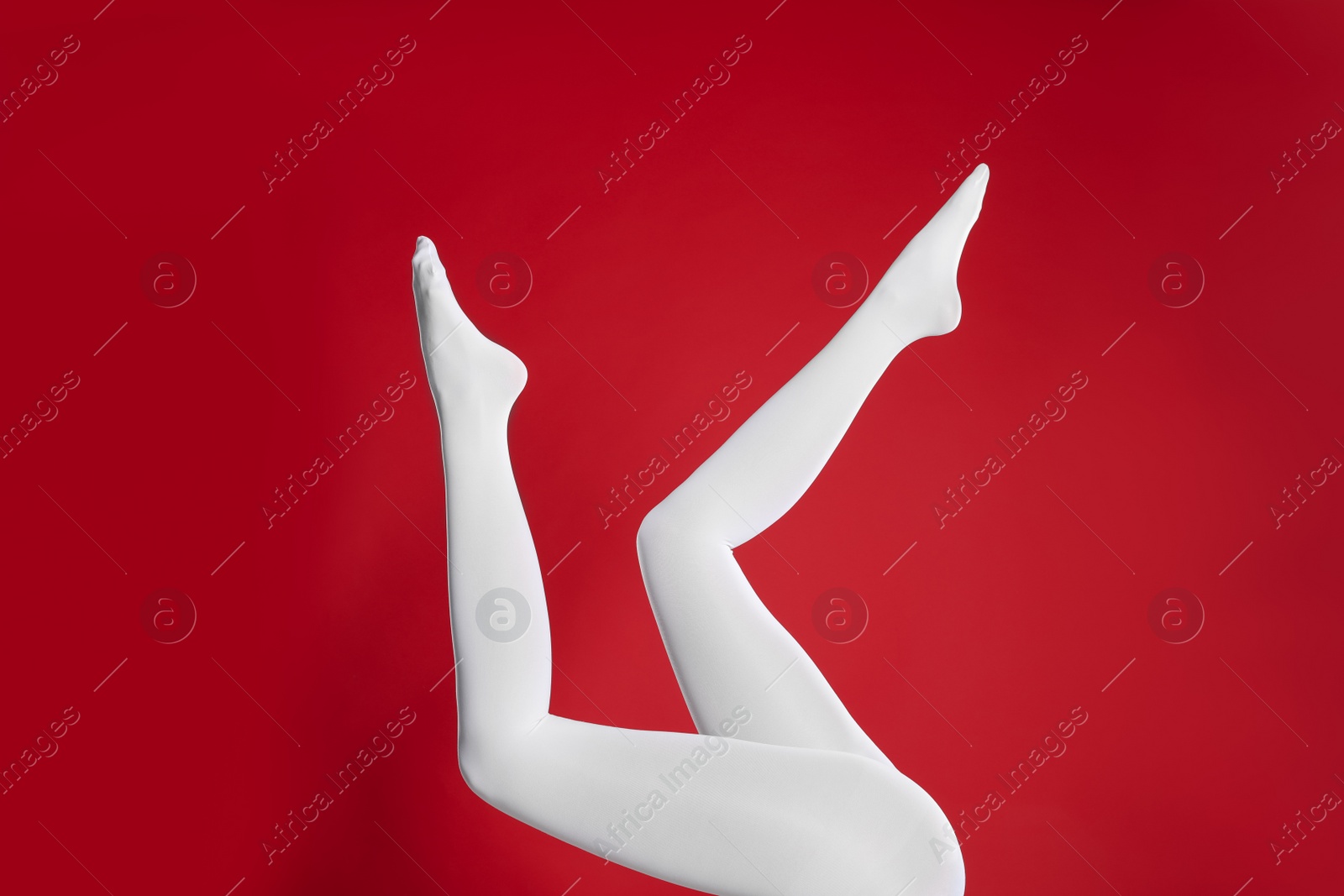 Photo of Woman wearing white tights on red background, closeup of legs