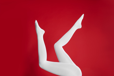 Photo of Woman wearing white tights on red background, closeup of legs