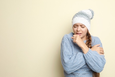 Image of Young woman wearing hat coughing on light background, space for text. Cold symptoms