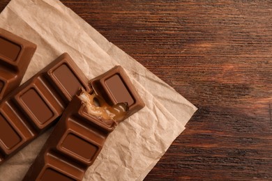 Photo of Tasty chocolate bars on wooden table, top view. Space for text