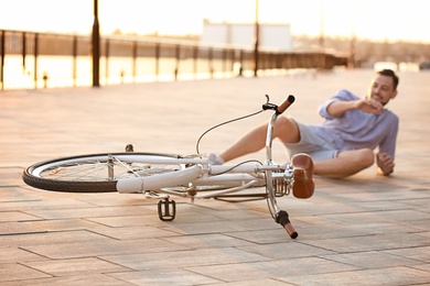 Photo of Man fallen off his bicycle on street, focus on bike