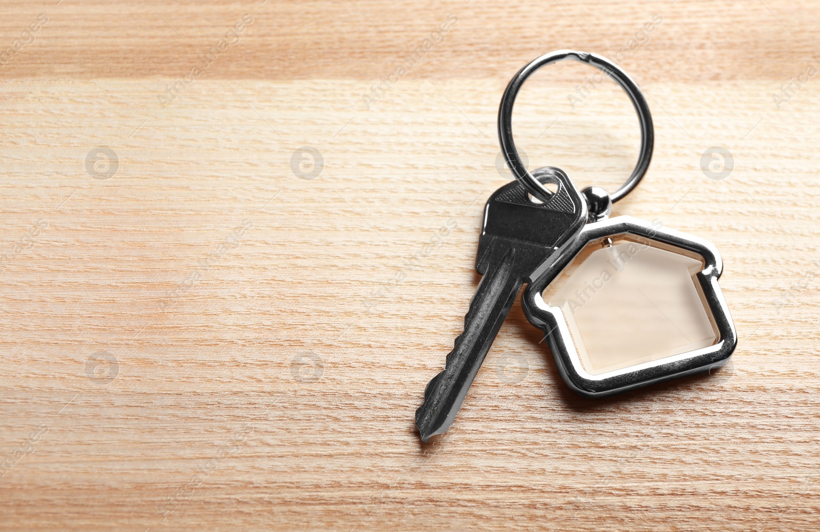 Photo of Key with trinket in shape of house on wooden background. Real estate agent services