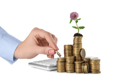 Photo of Woman putting coin onto stack with beautiful plant on white background, closeup