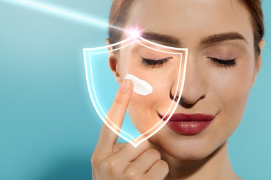 Beautiful woman applying sunscreen onto face against light blue background, space for text. Illustration of shield symbolizing sun protection