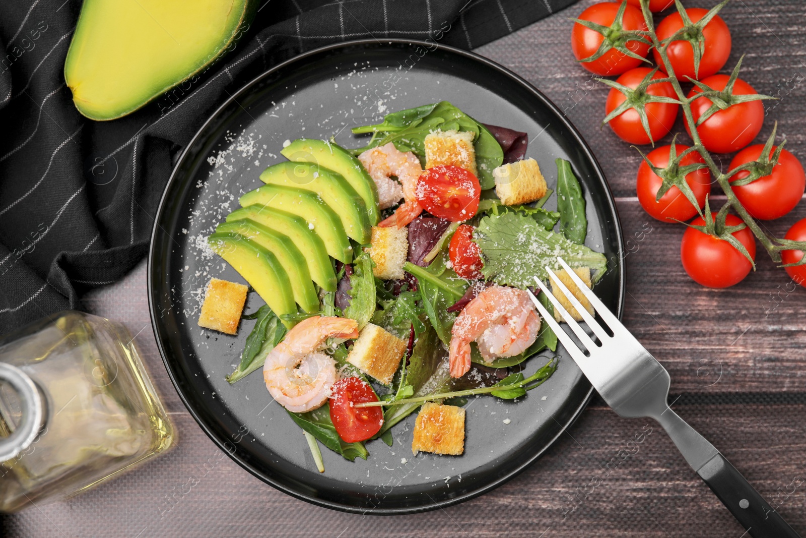 Photo of Delicious salad with croutons, avocado and shrimp served on wooden table, flat lay