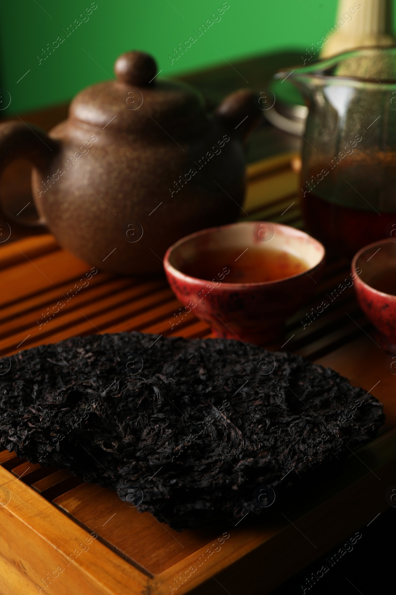 Photo of Broken disc shaped pu-erh tea on wooden tray, closeup