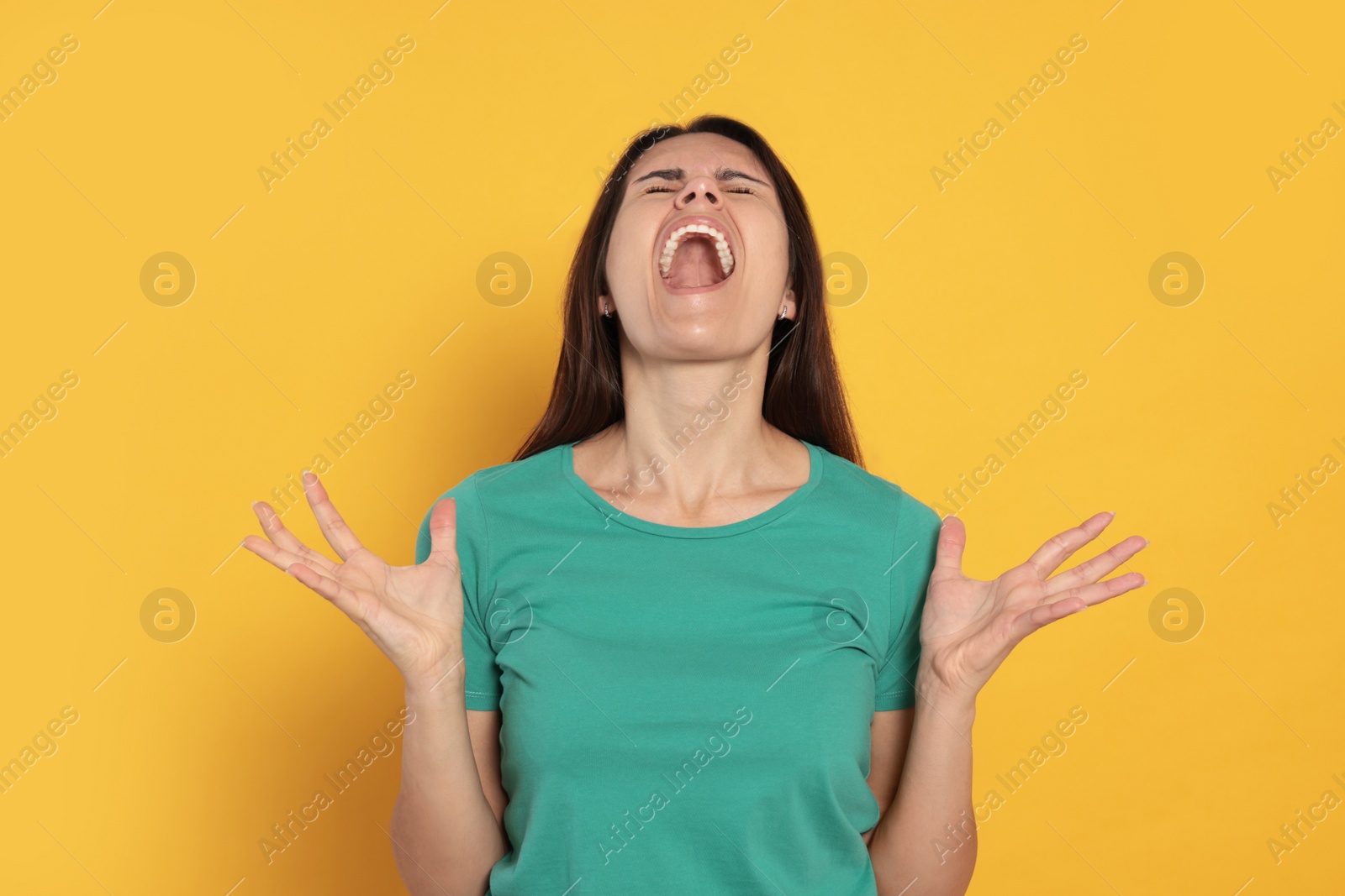 Photo of Aggressive young woman shouting on orange background