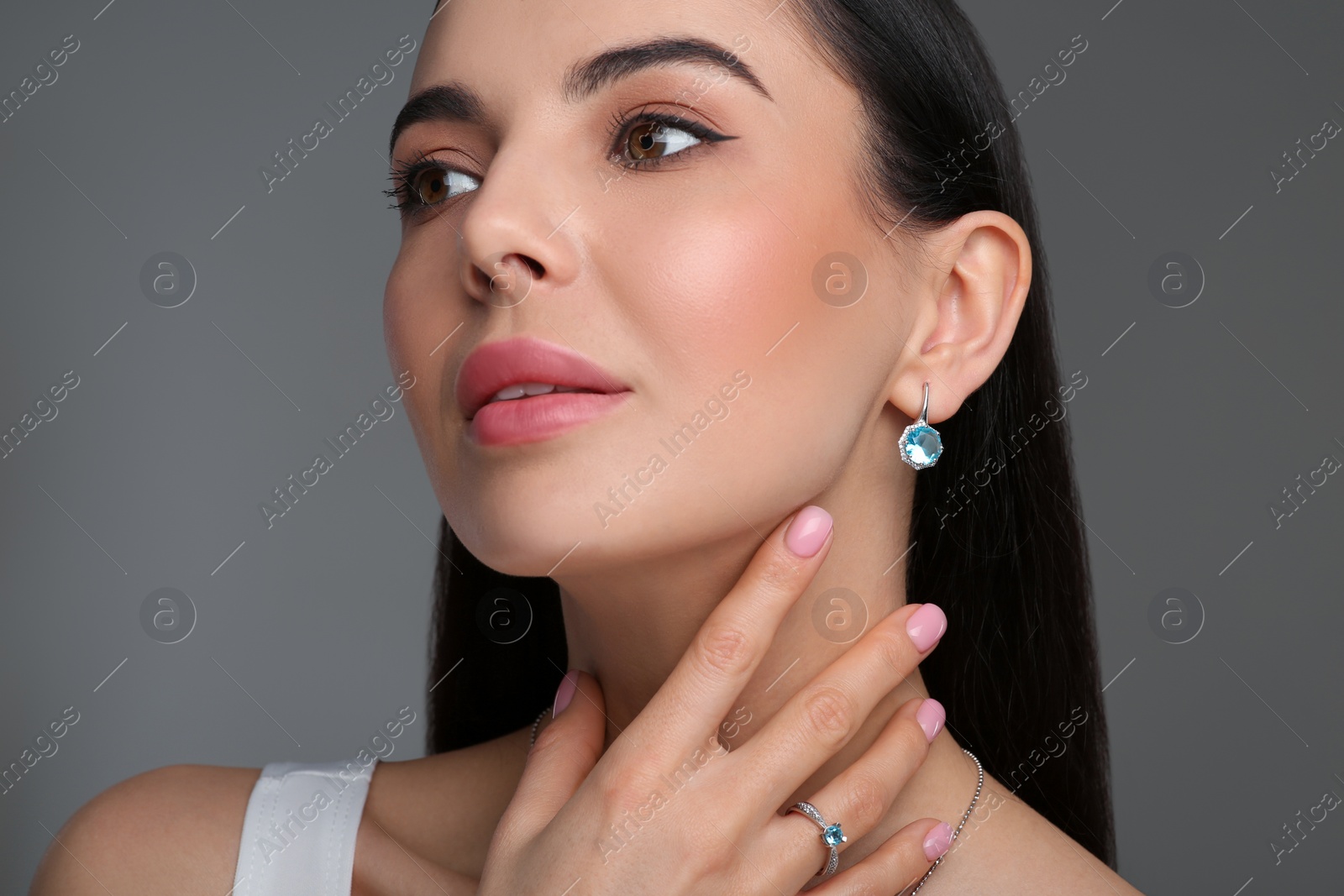 Photo of Beautiful young woman with elegant jewelry on dark grey background