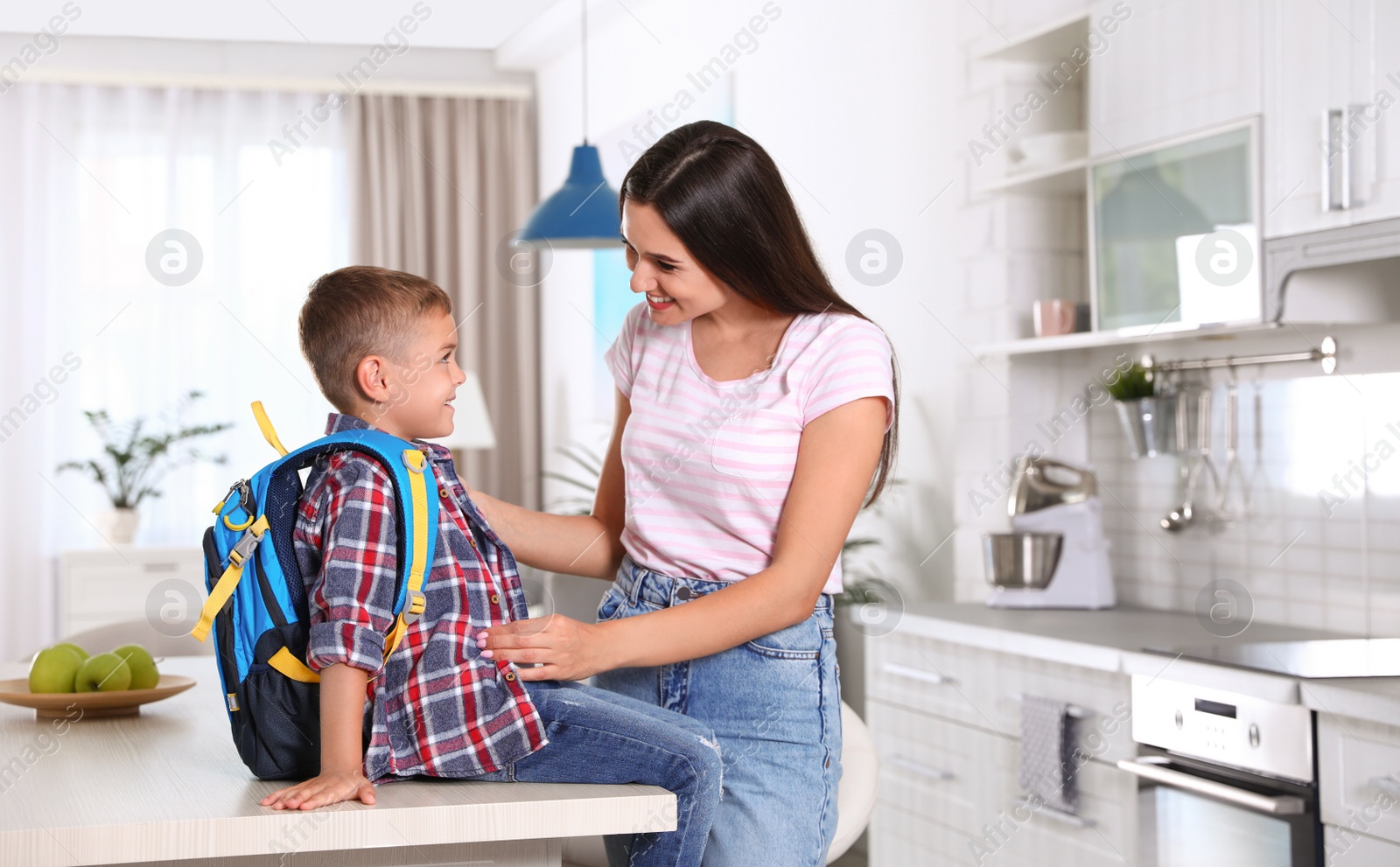 Photo of Happy mother and little child with backpack ready for school in kitchen