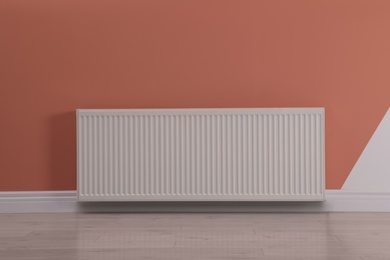 Photo of Modern radiator on color wall. Central heating system