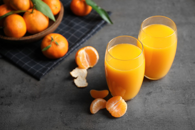 Photo of Fresh tangerines and glasses of juice on grey table