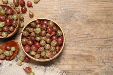 Photo of Many fresh ripe gooseberries on wooden table, flat lay. Space for text