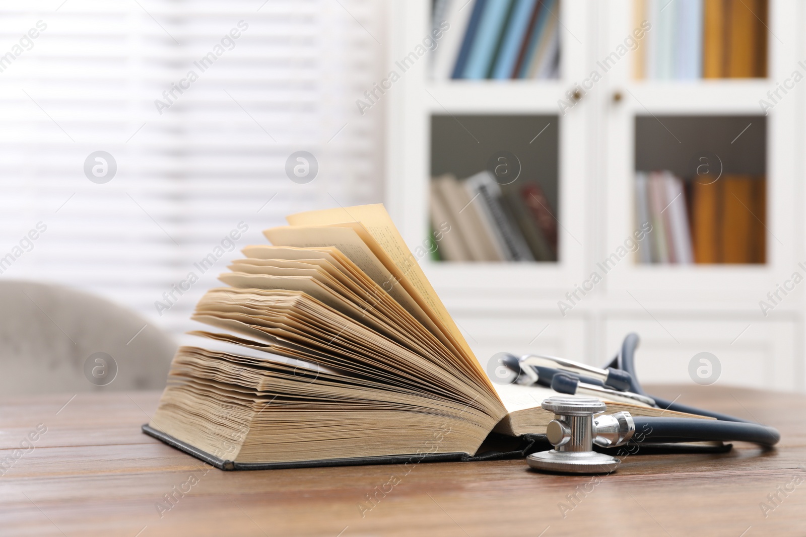 Photo of Book and stethoscope on wooden table indoors, space for text. Medical education