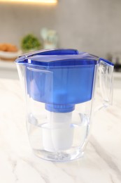 Photo of Water filter jug on white marble table in kitchen