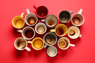 Many dirty cups after drinking coffee on red table, flat lay