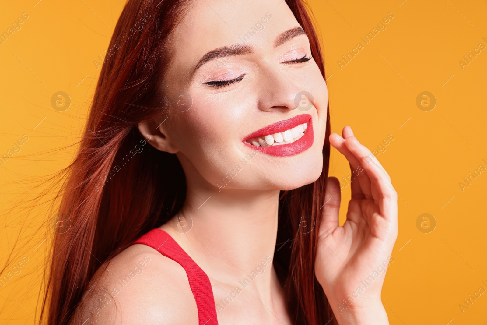 Photo of Happy woman with red dyed hair on orange background