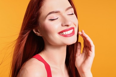 Happy woman with red dyed hair on orange background