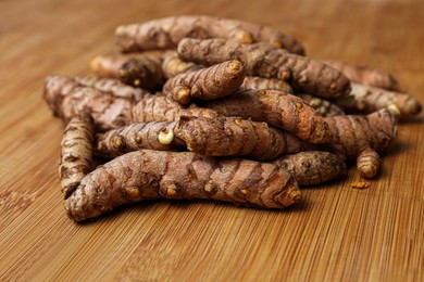 Photo of Many whole turmeric roots on wooden table
