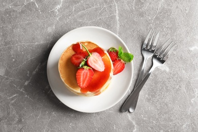 Plate with pancakes and berries on grey background, top view