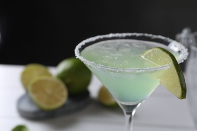 Photo of Delicious Margarita cocktail with ice cubes in glass and lime on table, closeup. Space for text