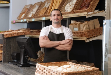 Photo of Portrait of professional baker at cashier desk near showcase in store