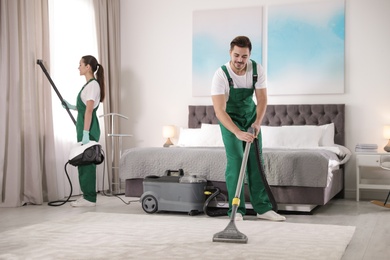 Team of janitors cleaning bedroom with professional equipment