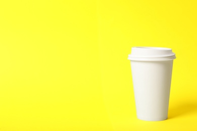 Takeaway paper coffee cup on yellow background. Space for text