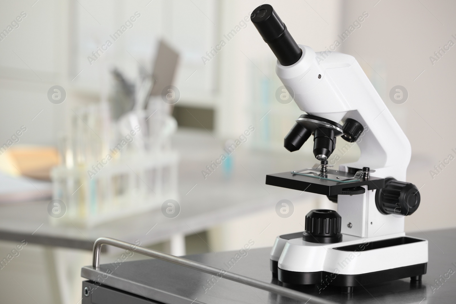 Photo of Modern medical microscope on metal table in laboratory, space for text