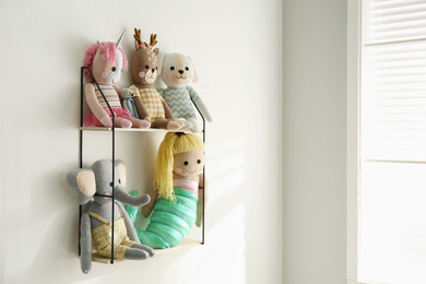 Photo of Shelf with cute toys on light wall indoors. Baby room interior element