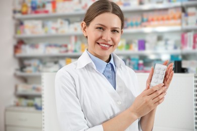 Photo of Professional pharmacist with pills in modern drugstore